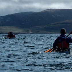 sea kayaking in the shadow of mountains